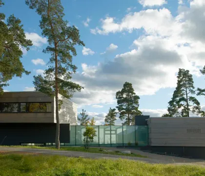 Villa med träfasad och stora fönster i grönskande tomt
