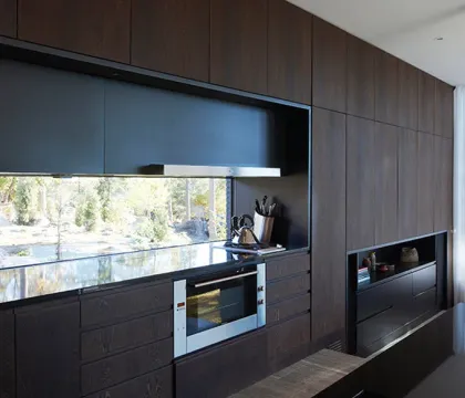Modern villa i mörk träpanel med stora glaspartier