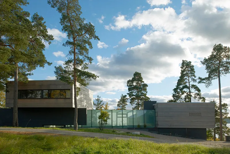 Villa med träfasad och stora fönster i grönskande tomt