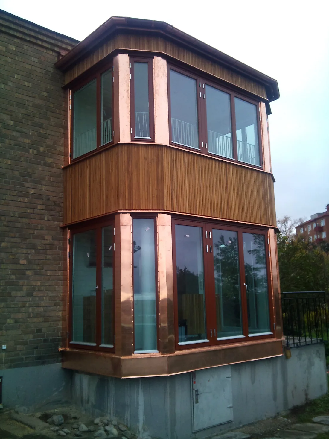 Rundad modern villa med inglasad sektion och träpanel